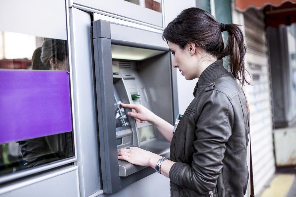 Young Caucasian woman withdrawing money from an ATM.