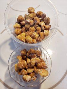 two containers of honey roasted macadamia nuts dusted in sugar and salt