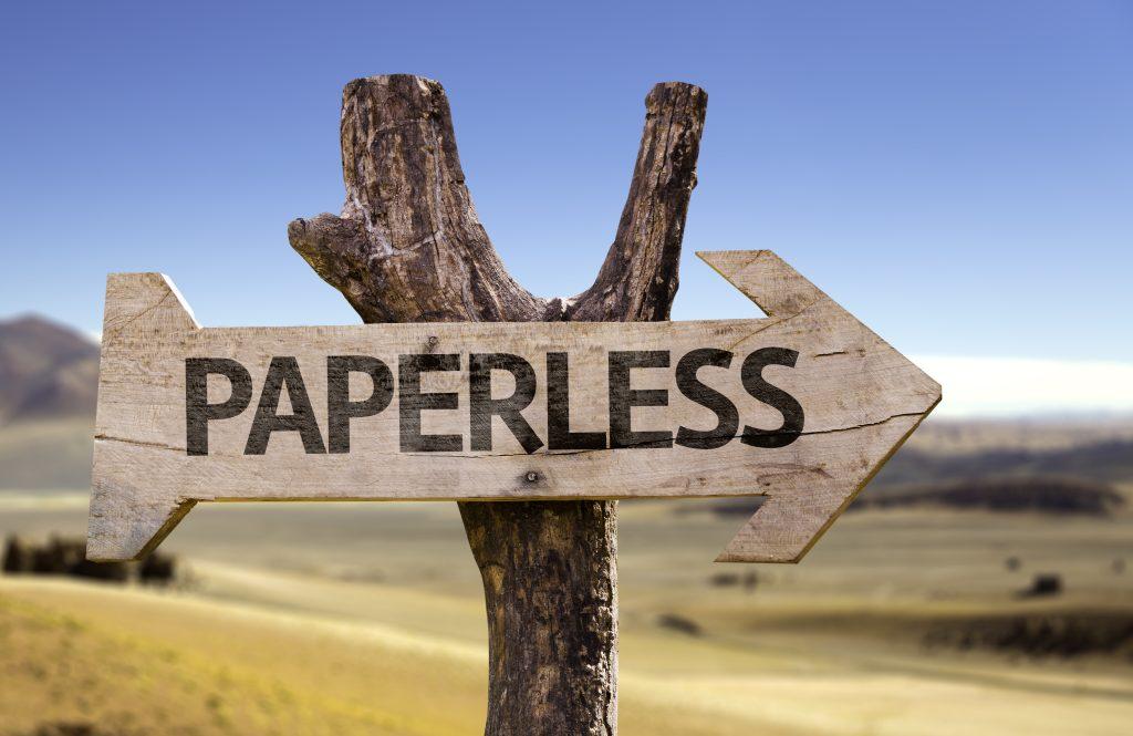 wooden arrow with the word paperless printed on it attached to a wood post