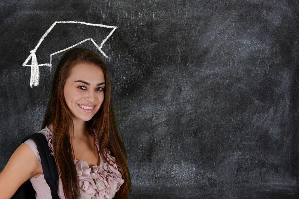 college student infront of a chalkboard with a graduation cap around her head