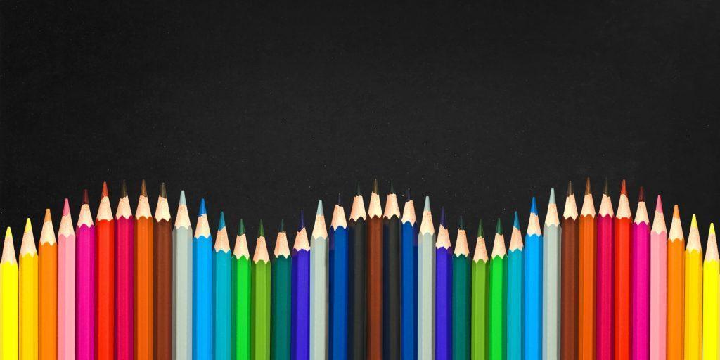 Wave of colorful wooden pencils isolated on a black board background