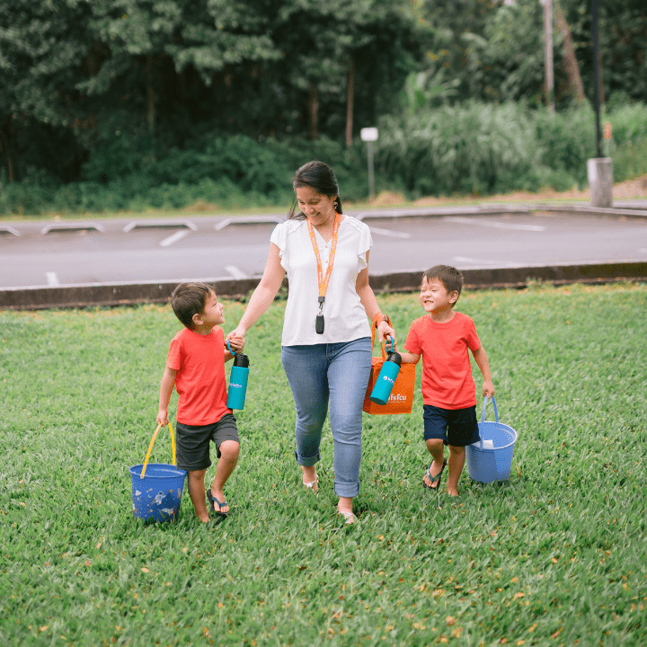 a mom walking with her young twin boys, holding hands
