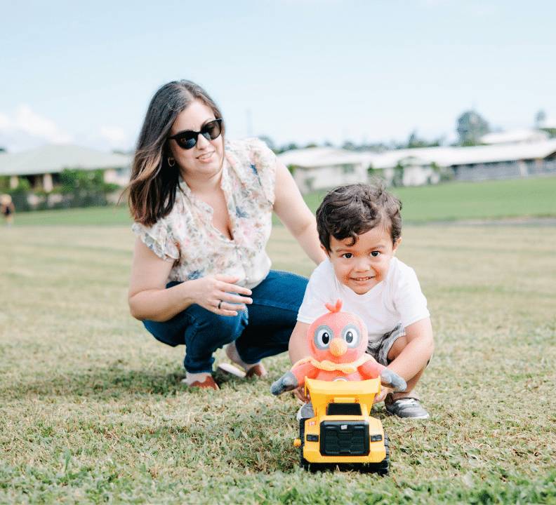 young boy with mom playing with dump truck and plushy